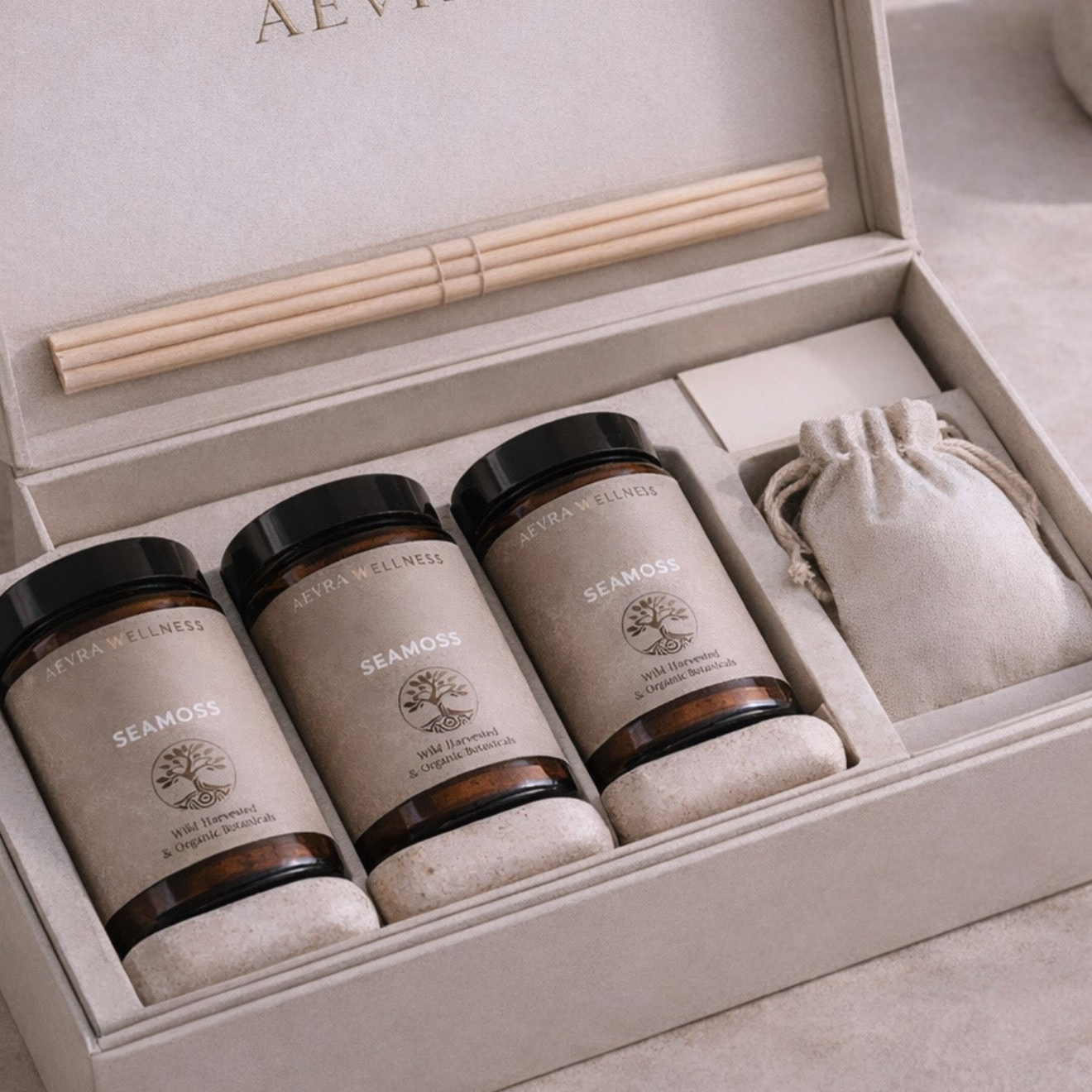 Three jars labeled 'Seamoss' in a decorative box with reeds and a drawstring bag.